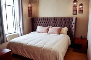 um quarto com uma cama grande com lençóis brancos e almofadas cor-de-rosa em Real Santuario em Guadalajara