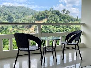 2 sillas y mesa en un balcón con vistas en The Green Golf Apartments en Ban Thung Thong