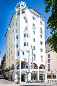 Un bâtiment blanc avec un panneau. dans l'établissement Hôtel Saint Georges, à Lourdes