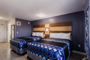 Coratel Inn & Suites by Jasper Inver Grove Heights في Inver Grove Heights: سريرين في غرفة فندق بجدران زرقاء