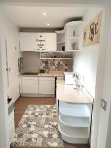 eine Küche mit weißen Schränken und einer Arbeitsplatte in der Unterkunft Maison de vacances in Bias