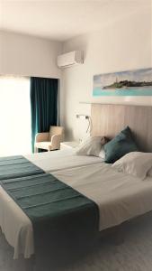 a bedroom with a large bed with a green blanket at Hotel Amic Gala in Can Pastilla