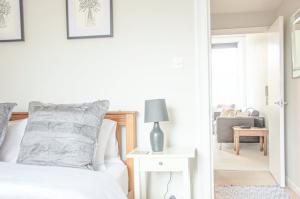 a white bedroom with a bed and a chair at Beautiful Georgian One Bedroom Apartment in Bath