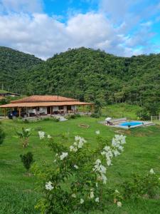 a house in the middle of a field with a pool at Refúgio dos Moreiras in Monteiro Lobato