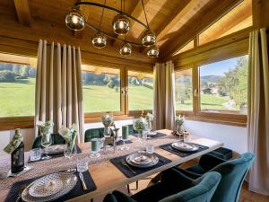 a dining room with a table and chairs and windows at Das Kaiserwohl Chalet in Going