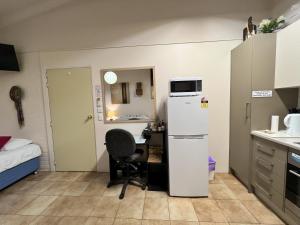 a small kitchen with a desk and a refrigerator at Westside Studio Apartments in Armidale