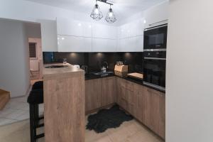 eine Küche mit Holzschränken, einer Spüle und einer Mikrowelle in der Unterkunft ŁOSOSINA 365 Dom z basenem 