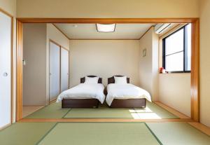 2 Betten in einem Zimmer mit großem Spiegel in der Unterkunft Rakusansui Villa in Itoshima