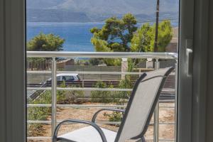 una sedia seduta su un balcone affacciato sull'oceano di Enchanted Sunlit Villa Retreat a Isthmia