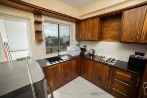 cocina con armarios de madera, fregadero y ventana en BNB RESIDENCE MOUNT LAVINIA 1, en Mount Lavinia