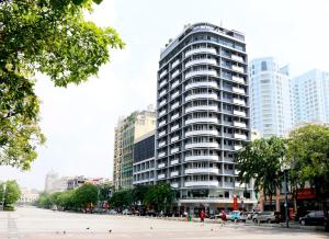 Ein hohes Gebäude mit Leuten, die davor laufen. in der Unterkunft Palace Hotel Saigon in Ho-Chi-Minh-Stadt