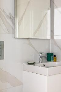 Baño blanco con lavabo y espejo en Kensington High Street Apartments en Londres