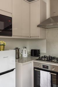 a kitchen with white cabinets and a stove top oven at Kensington High Street Apartments in London