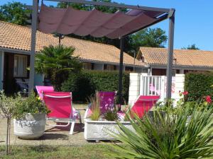a group of pink chairs and plants in a yard at Hotel Les Pins in Hourtin