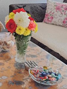 a vase of flowers on a table with a bowl of candy at OAZA ZA DUŠU in Visoko