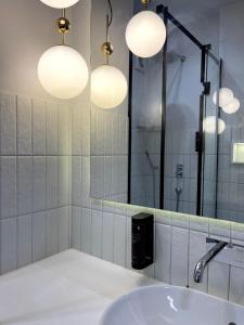 een badkamer met een wastafel, een spiegel en verlichting bij Atlant luxury VIOLET Apart on Golovna стильні апартаменти поряд з ТЦ ДЕПОТ БЕЗКОНТАКТНЕ ЗАСЕЛЕННЯ in Tsjernivsi