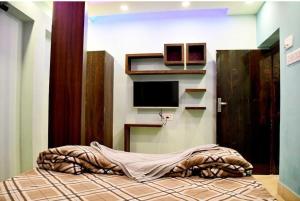 a bedroom with a bed with a tv on the wall at Super OYO The Orchid Residency in Kolkata