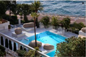 a swimming pool on a balcony next to the ocean at Elegant Monaco Port de Fontvieille apartment with Garden View and Pool Access in Monte Carlo