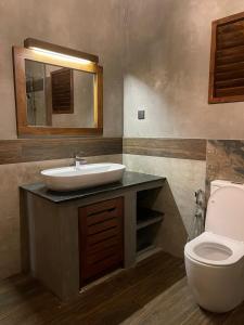 a bathroom with a sink and a toilet at Adique's Resorts in Marawila