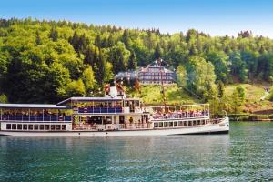a cruise ship on the water in front of a house at Holiday flats Seehaus Gaby Maria Wörth am Wörthersee - OKT01013-SYA in Reifnitz