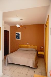 a bedroom with a bed and a orange wall at Halykos Hotel in Cammarata