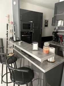 une cuisine avec un comptoir avec deux chaises et un comptoir dans l'établissement Appartement - Chic et Cosy à 30 minutes de Paris et 25 minutes de Disney, à Ozoir-la-Ferrière