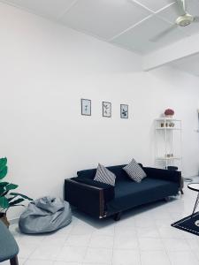 - un salon avec un canapé noir dans une pièce blanche dans l'établissement Comfort Semi D House, 1 min to Town by Mr Homestay, à Teluk Intan