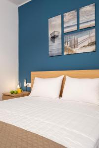 a bedroom with a white bed with a blue wall at Urban Elegance - City Center 3-Bedroom Apartment in Chania
