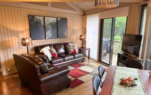 a living room with a leather couch and a table at Chalet 141 - Peaceful wooded views cozy interiors plus wifi in Marblehill