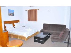a bedroom with a bed and a chair and a couch at Lamerinn Hotel Juba in Juba