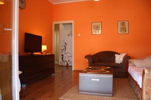 sala de estar con paredes de color naranja, sofá y TV en Apartment Sendy, en Zadar