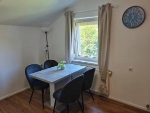 a dining room table with chairs and a clock on the wall at StayEasy Apartments Ramingtal #1 