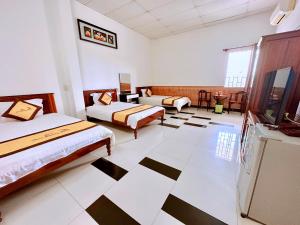 a bedroom with two beds and a checkered floor at Trúc Hoàng Hà Hotel in Kon Tum