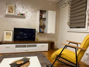 ein Wohnzimmer mit einem TV und einem gelben Stuhl in der Unterkunft Martina Lux in Belgrad