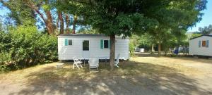 ein weißes Haus mit Stühlen, einem Tisch und einem Baum in der Unterkunft ARDECHO O'HARA B in Saint-Lager-Bressac