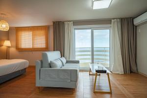 um quarto com uma cama, uma cadeira e uma janela em Hong Yang em Jeju