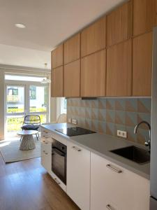 a kitchen with white cabinets and a sink and a table at Apartment Fontanu Namai in Vilnius