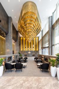 a lobby with a large chandelier and tables and chairs at Meriton Suites Canberra in Canberra