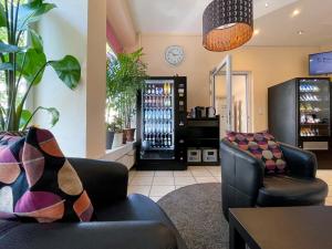 Zimmer mit 2 Sofas und einem Kühlschrank für Getränke in der Unterkunft Hotel Sendlinger Tor in München