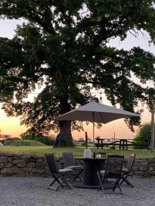 a table with an umbrella and chairs under a tree at Gites Le Grand Tornage holiday fun for the whole family in Évaux-les-Bains
