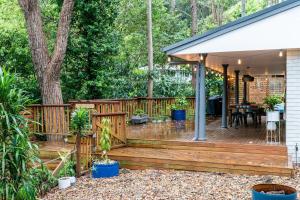 a wooden deck in a backyard with a tree at Woodlands Seaside - Coastal Calm in Avoca Beach in Avoca Beach
