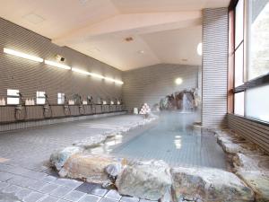 a swimming pool with a waterfall in the middle of a building at 多武峰観光ホテル in Sakurai