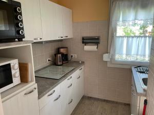 a small kitchen with white cabinets and a microwave at Bungalow am Schwielochsee 2.0 in Schwielochsee +5 photos