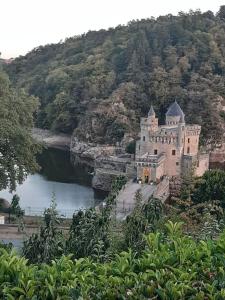 a castle on a hill next to a body of water at Loft avec SPA privatisé in Sainte-Foy-Saint-Sulpice