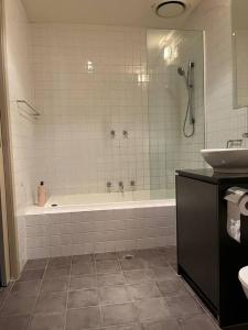 a bathroom with a bath tub and a sink at Spacious, Central 2 QB Melbourne CBD Apt near Flinders Stn, Town Hall in Melbourne