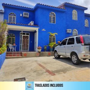 una furgoneta estacionada frente a una casa azul en BELLA SUITE frente al Aeropuerto, en Catia La Mar
