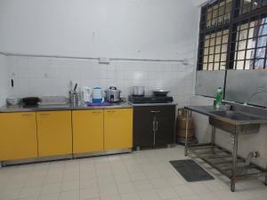 uma cozinha com armários amarelos e um lavatório em SDA Homestay Pool @StadiumDarulAman Untuk Muslim Sahaja em Alor Setar