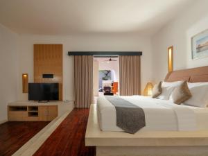 a bedroom with a large bed and a flat screen tv at The Seminyak Suite - Private Villa in Seminyak