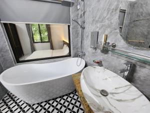 ein Badezimmer mit einer Badewanne, einem Waschbecken und einem Spiegel in der Unterkunft KL Retreat Hotel in Thanh Hóa