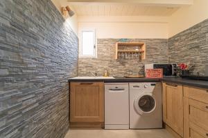 cocina con lavadora y pared de ladrillo en La Bastide des Pins, en Castillon-du-Gard